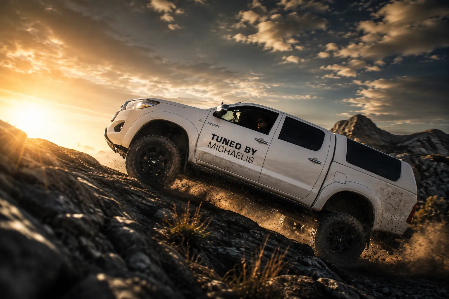 Weißer Toyota Hilux von Michaelis Tuning klettert im Sonnenuntergang über felsiges Gelände